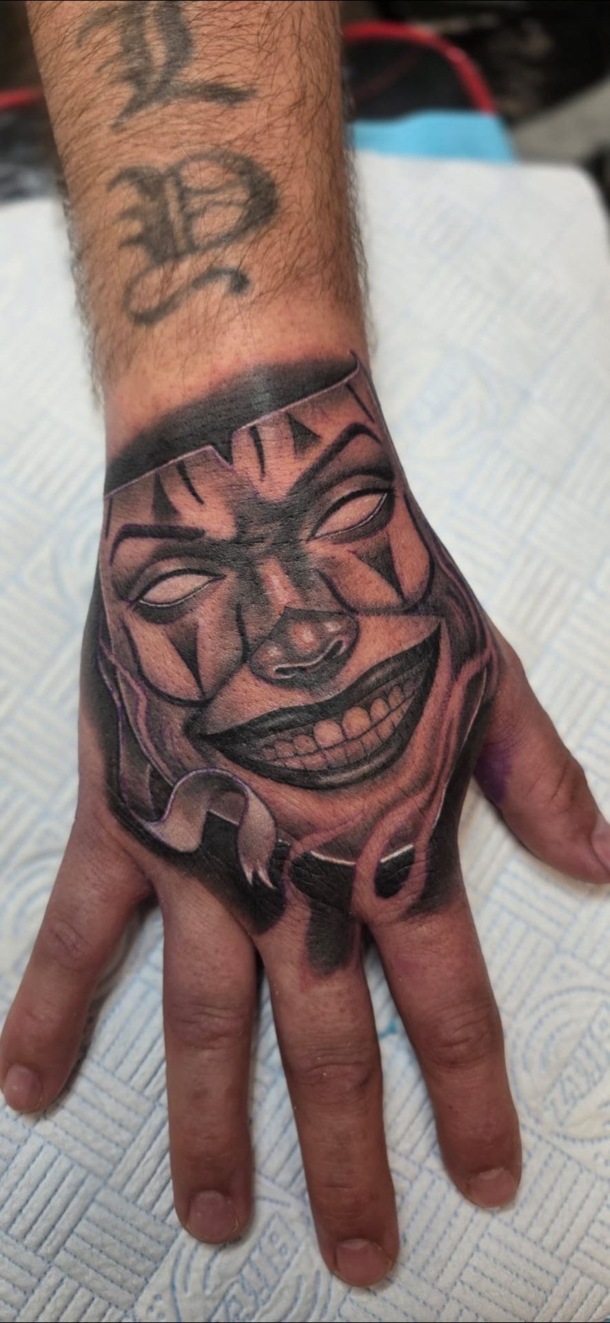 Chicano clown hand tattoo in black and grey