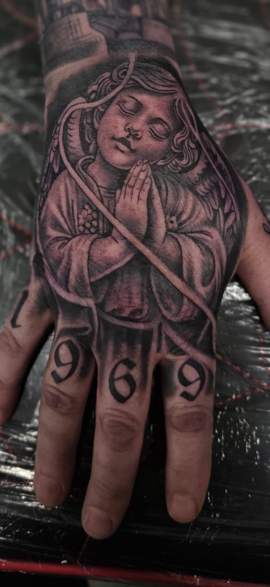 Praying cherub hand tattoo with 1969 finger lettering